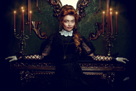 The Victorian era concept. Beautiful woman in elegant historical dress and hairstyle posing in vintage interior. Baroque. Fashion.の写真素材