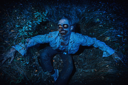 Zombie climbs out of the grave in the night cemetery. Halloween. Horror.