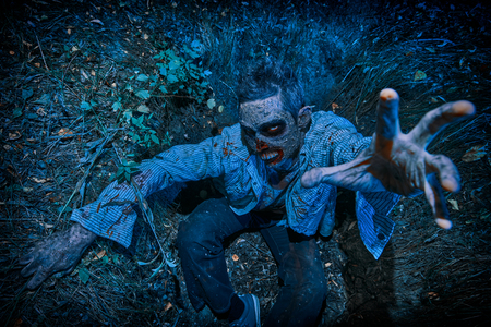 Zombie climbs out of the grave in the night cemetery. Halloween. Horror.の写真素材