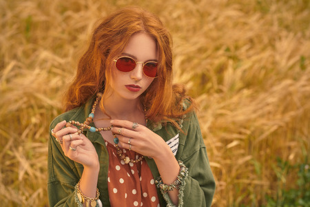 Portrait of a modern hippie girl in a wheat field. Bohemian style.の写真素材
