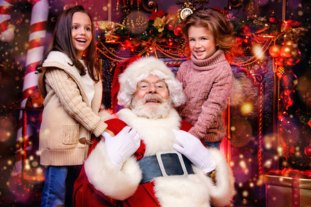 Two happy girls are at home with Santa Claus. Miracle time. Christmas, New Year.の写真素材