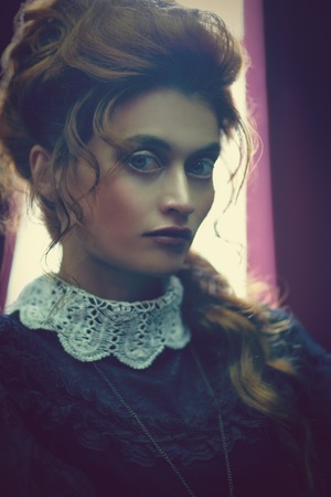 The Victorian era concept. Portrait of a beautiful woman in elegant historical dress and hairstyle posing in vintage interior. Baroque. Fashion.の写真素材