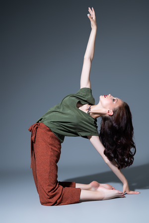 A full length portrait of a beautiful young woman dancing over the grey background in the studio. Casual fashion, fitness, yoga.の写真素材