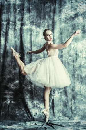 A full length portrait of an elegant refined female ballet dancer posing in the studio over the grunge background. Talent, fashion for ballet dancers.の写真素材