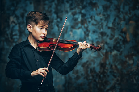 A portrait of a boy in his teens playing the violin. A creative, talented, gifted boy.の写真素材