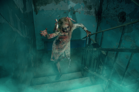Scary zombie girl is standing on the stairs. Halloween. Horror movie.の写真素材