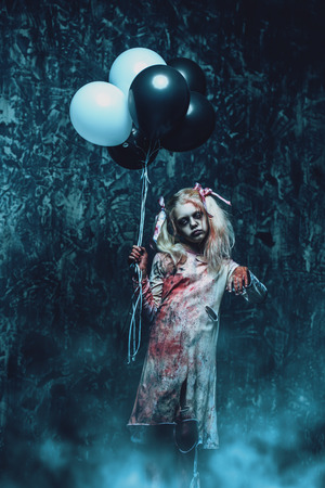 A scary zombie girl holding balloons. Halloween. Horror film.の写真素材