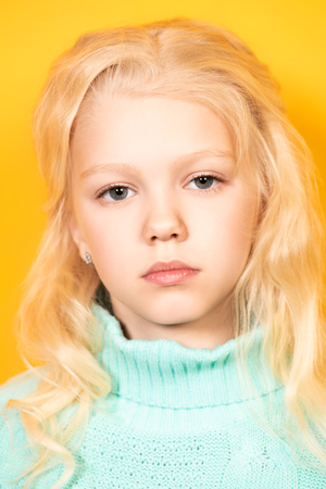 A cute emotional girl in glasses is posing over the yellow background. Beauty, fashion for kids.の写真素材