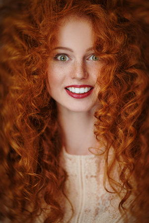 Beautiful smiling girl with long red hair. Hair care, hair coloring. Copy space.の写真素材