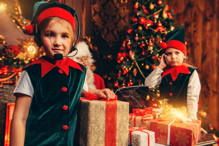 Two fabulous girls help Santa Claus to pack gifts at home. Merry Christmas and Happy New Year. Miracle time.の写真素材