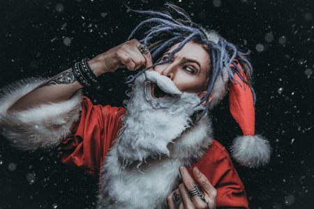 Portrait of a cool punk Santa Claus with bright dreadlocks over black background.の写真素材