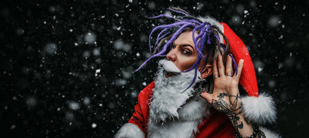 Portrait of a cool punk Santa Claus in luminous glasses with bright dreadlocks over black background.の写真素材