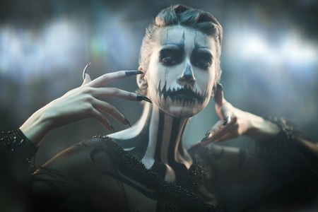 Portrait of a beautiful young woman with Halloween pumpkin skeleton makeup over mysterious foggy background. Pumpkin queen. Day of The Dead.の写真素材