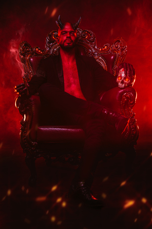 A portrait of a bad demon in his throne with a skull and cigar. Horror movie, nightmare. Halloween.の写真素材