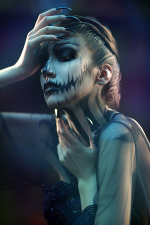 Portrait of a beautiful artistic young woman with Halloween skeleton makeup over dark background. Pumpkin queen. Day of The Dead.の写真素材