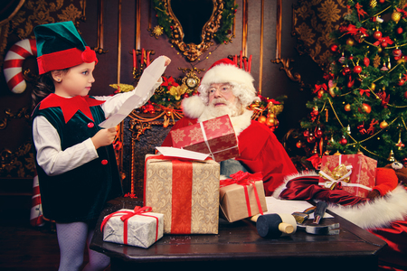 A happy young girl reads Santa a letter with wishes for Christmas. Merry Christmas and Happy New Year. Miracle time.の写真素材