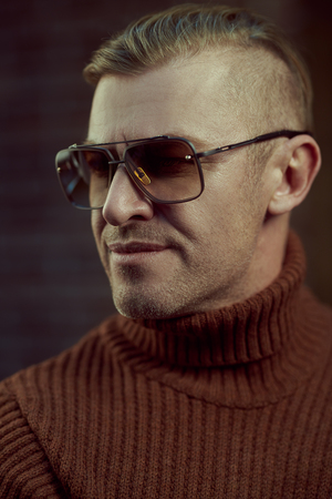 Handsome mature man in sunglasses over brick wall background. Optics style.の写真素材