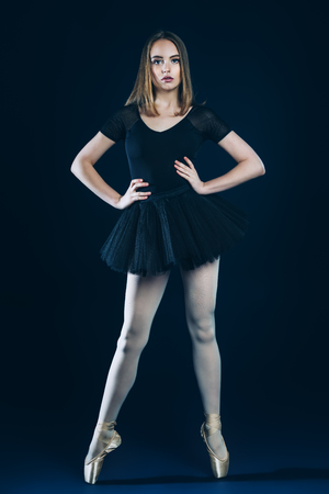 A full length portrait of an elegant refined ballet female dancer posing in the studio over the black background. Talent, fashion for ballet dancers.の写真素材