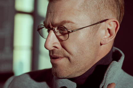 Close-up portrait of a handsome middle aged man in elegant clothes and glasses standing by the...