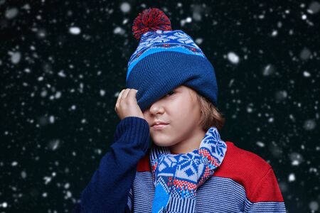 Portrait of a cute emotional boy child in winter clothes under the snow.の写真素材
