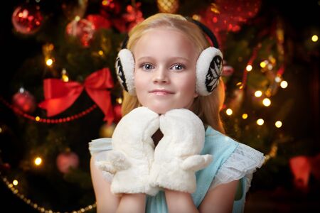 Merry Christmas and Happy New Year! Happy cute girl celebrates Christmas by a beautiful Christmas tree. The atmosphere of magic, lights and sparkle is around.の写真素材