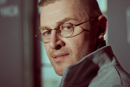 Close-up portrait of a handsome middle aged man in elegant clothes and glasses standing by the...