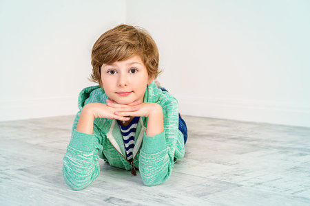 Pretty happy nine-year girl lying on a floor and smiling. Children's fashion. Education. Activity...
