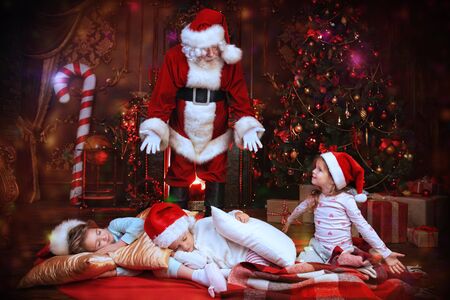 Santa Claus is putting gifts while children are sleeping at home. Merry Christmas and Happy New Year. Miracle time.の写真素材