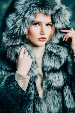 A portrait of a beautiful woman wearing a fur coat with hood. Beauty, winter fashion, style.の写真素材