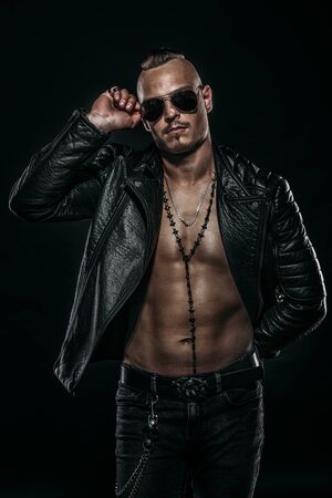 Dark portrait of a serious gangster man with  gun wearing black leather jacket.の写真素材