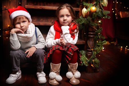 Two cute children boy and girl in festive clothes in Christmas atmosphere Christmas and New Year concept.の写真素材
