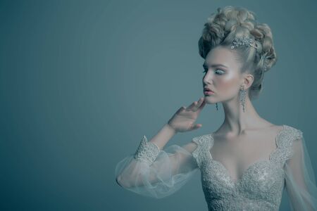 A portrait of a cold beautiful lady wearing a fluffy dress and posing in the studio over the blue background. Beauty,cosmetics, hairstyle, fashion.の写真素材