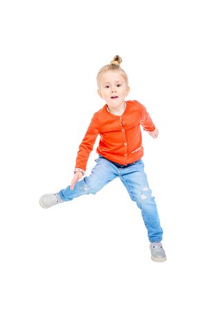 A portrait of a cute bright girl jumping in the studio over the white background. Kids, casual fashion.の写真素材