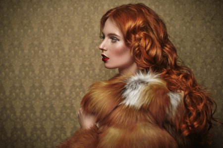 Beautiful young woman with magnificent red hair posing in a luxurious fox fur coat on a vintage...
