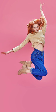 Fashion shot. Beautiful expressive girl in modern casual clothes posing at studio in motion over...