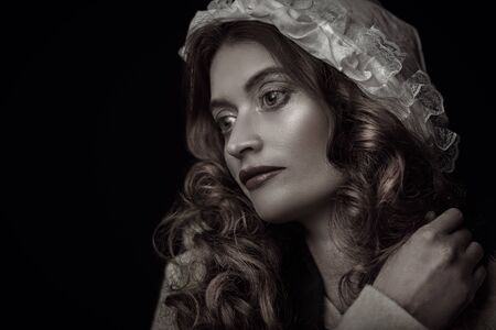 Close-up portrait of a beautiful young woman with long red hair wearing medieval clothes. Historical reconstruction of the Middle Ages. Sepia portrait.の写真素材