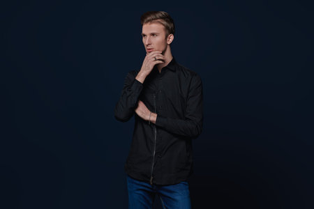 Men's beauty, fashion. Portrait of a handsome young man posing at studio on a dark blue background.