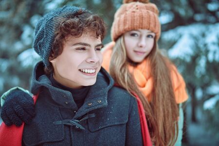 A young man and his girlfriend walk happily in the winter forest. Winter season, winter activities.の写真素材