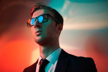 Men's fashion. Portrait of a handsome man in a formal suit in red and green light. Businessman studio portrait.の写真素材
