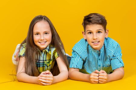 A portrait of two cheerful young kids over the yellow background. Summer casual kids fashion.の写真素材