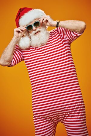 Portrait of the good old Santa Claus in a beach suit and boots on a yellow background. Merry Christmas and Happy New Year! Copy space.の写真素材