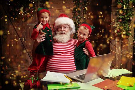 Santa Claus and little elves are sorting mail, reading letters from children. House, workshop of Santa Claus.の写真素材