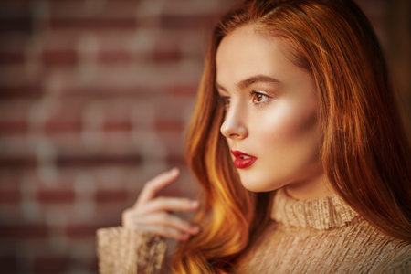 Close-up portrait of a pretty young girl with natural make-up and in a light beige dress looking...