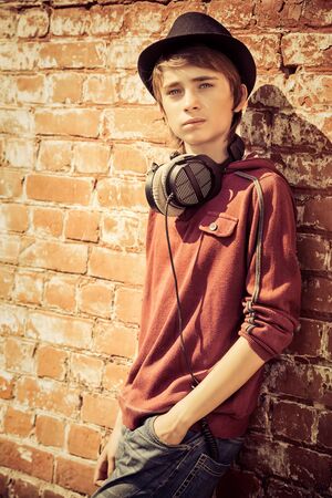 A portrait of a young goodlooking guy in red sweatshirt over the brick wall. Beauty of men, casual fashion.の写真素材