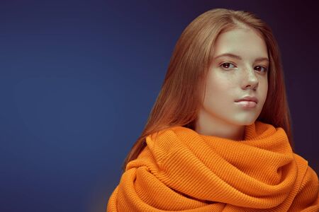 Happy girl teenager with lovely freckles on her face smiling at camera. Studio portrait on a dark background. Copy space.の写真素材