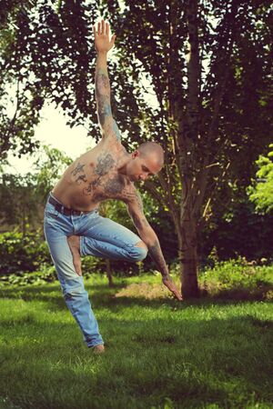 Portrait of a man is practicing yoga on on the grass in the Park. Fitness, yoga.の写真素材