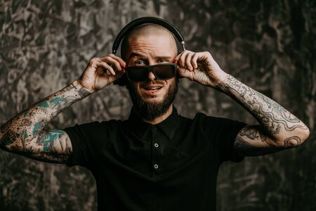 Brutal bearded man wearing sunglasses listenig to music in headphones and smiling.の写真素材