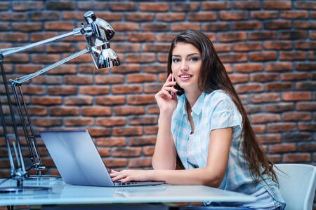 A beautiful lady sitting at a table. Office life. Work place.の写真素材