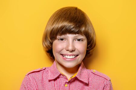 Portrait of a happy smiling boy over bright yellow background. Kid's fashion.の写真素材