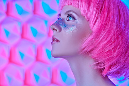 Portrait of an attractive girl with shiny glitter freckles and a bright pink wig on a background...